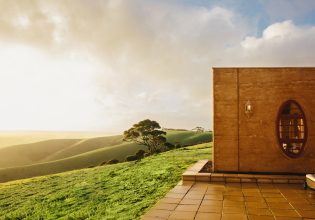 The Sky House on Kangaroo Island, atop a grassy hill with sun shining.