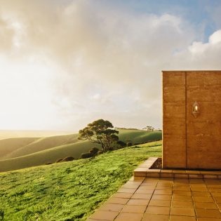 The Sky House on Kangaroo Island, atop a grassy hill with sun shining.