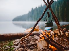 Campfire with a vintage kettle next to the beautiful lake.