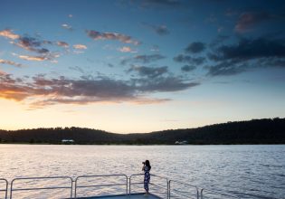 Woman taking photos of the sun setting over the Clarence River, Maclean