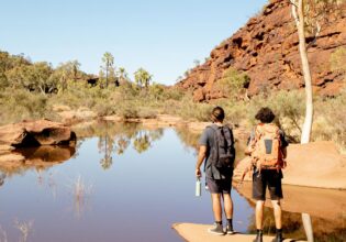 Two men hiking beside Finke River in Finke Gorge National Park