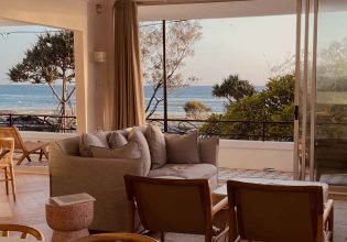 a living room with curtains opening up to scenic sea views