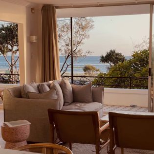 a living room with curtains opening up to scenic sea views
