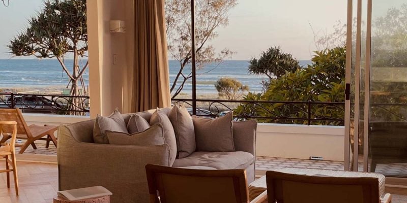 a living room with curtains opening up to scenic sea views