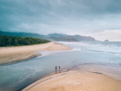 Two people crossing a beach along the Thorsborne Trail