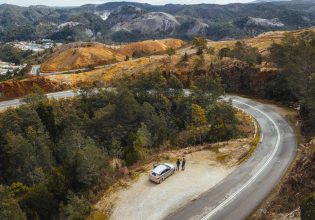 An aerial view of a car with people next to a winding road in Queenstown, Tasmania. (Image: Jason Charles Hill)